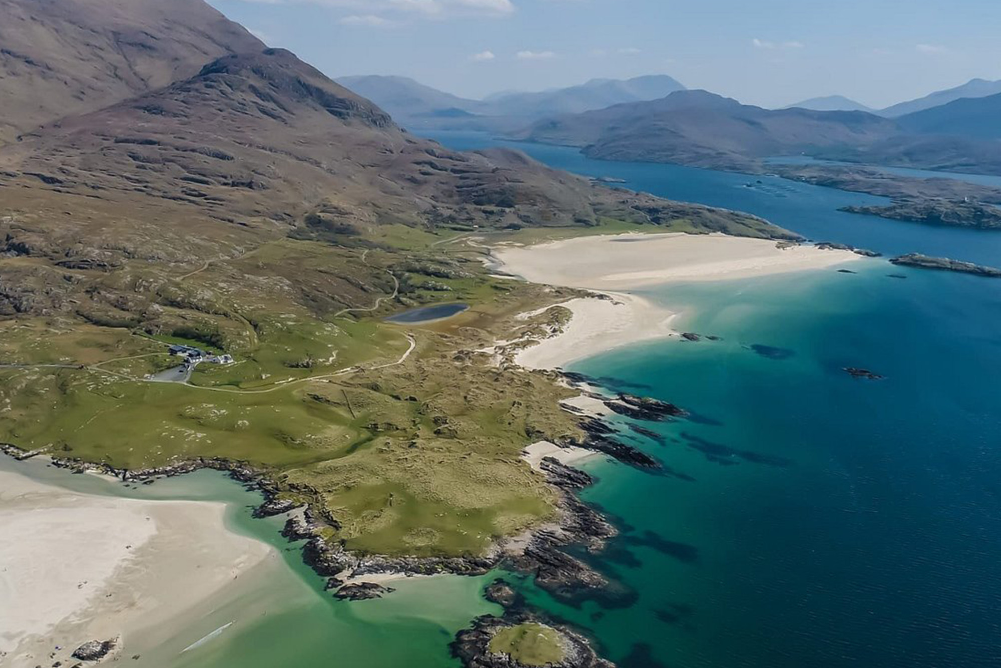 Aerial view of silver beach and turquoise sea at Old Head, County Mayo, Ireland, bordered by rugged hills.